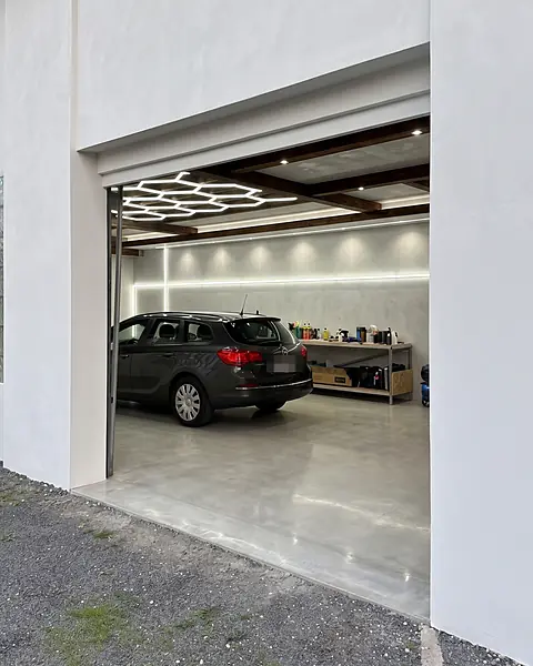 KI-Visualisierung: Einfahrt ins Studio, drinnen ein Auto unter dem Waben-Licht